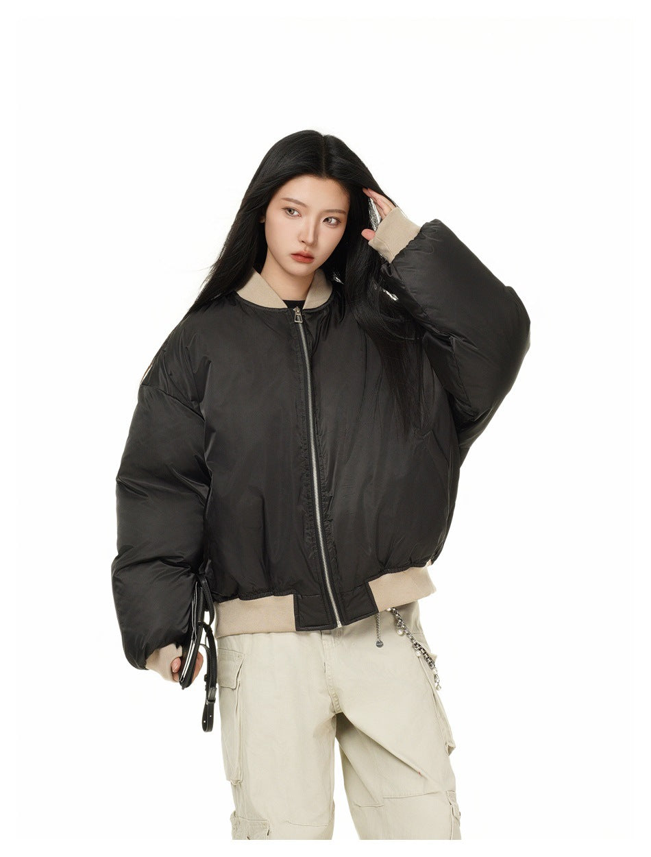 Model wearing a zipped black bomber jacket with beige ribbed trim and light cargo pants
