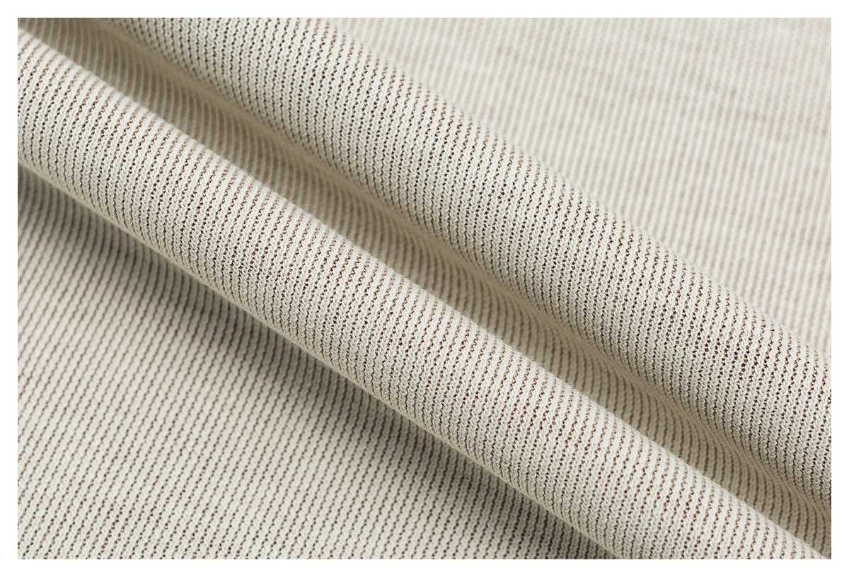 Macro view of cream fabric with fine brown ribbing, folded into soft ridges.