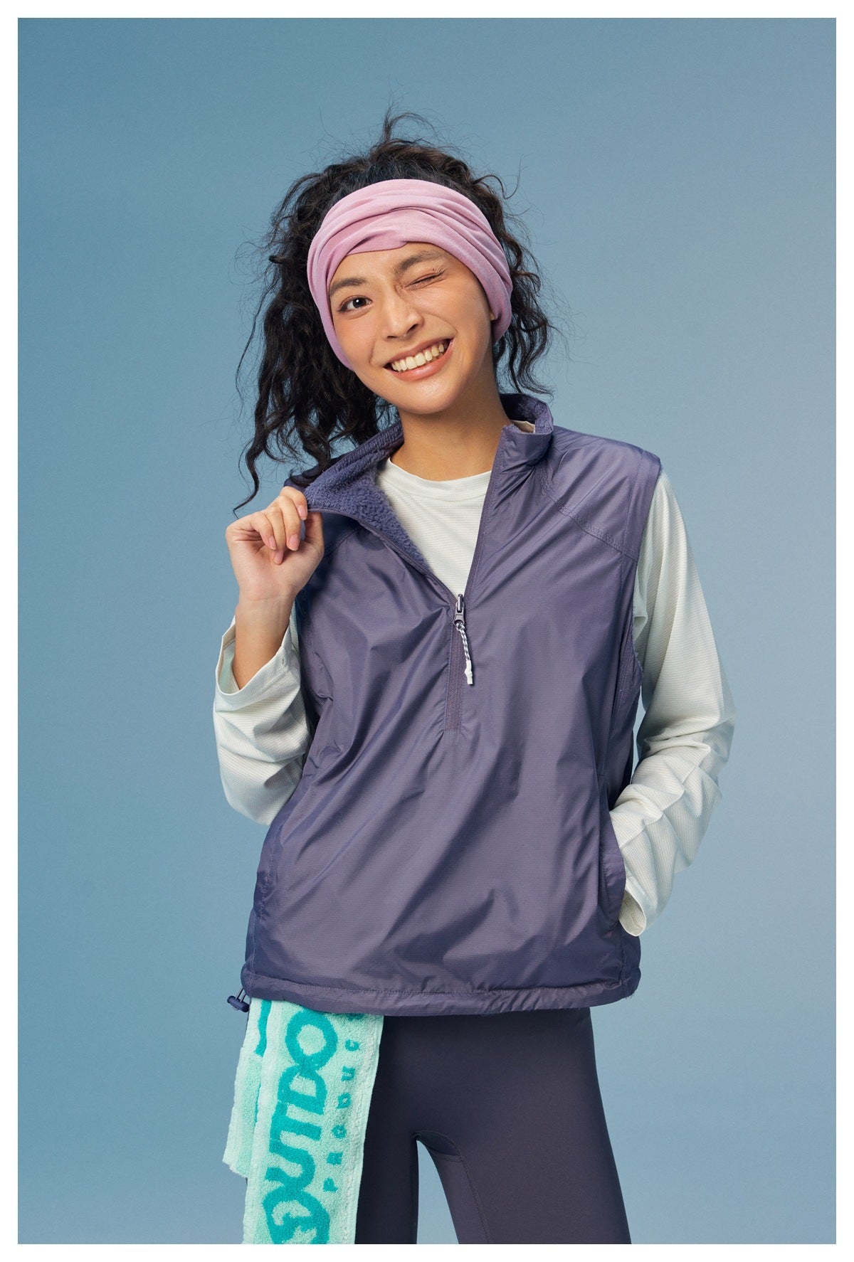 Model wearing a lavender quarter-zip sleeveless vest over a white long-sleeve top.