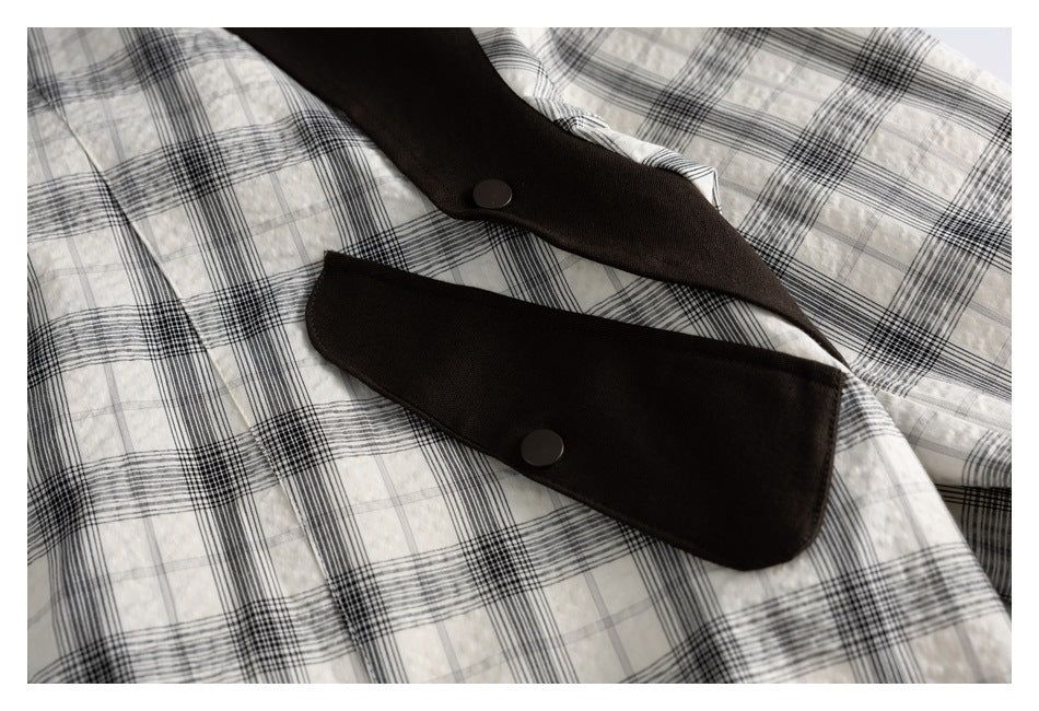 Close-up of dark brown snap-button flaps over the black-and-white plaid jacket front.