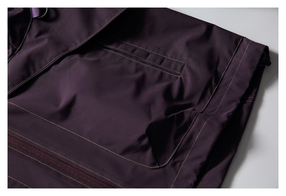 Close-up of a dark plum garment showing a large stitched pocket and nearby zipper.