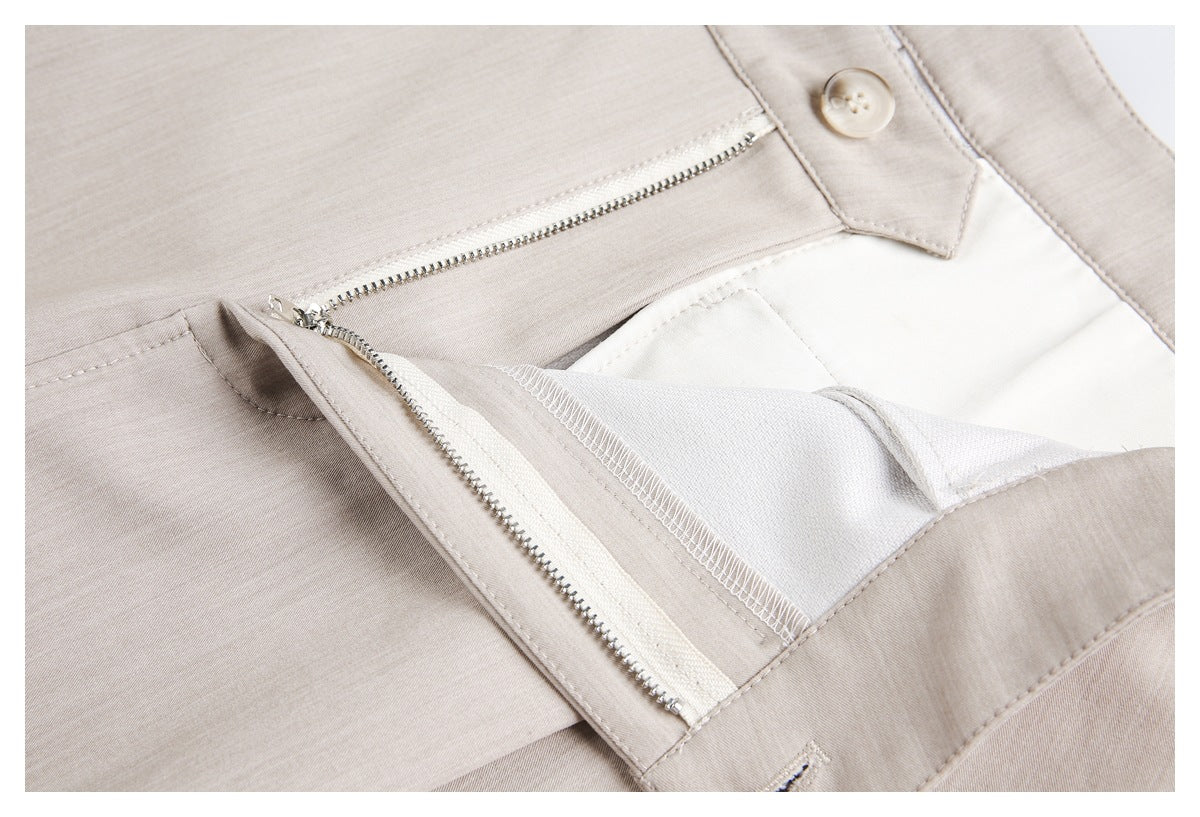 Close-up of beige trousers with the button and front zipper fly opened to show the inner lining.