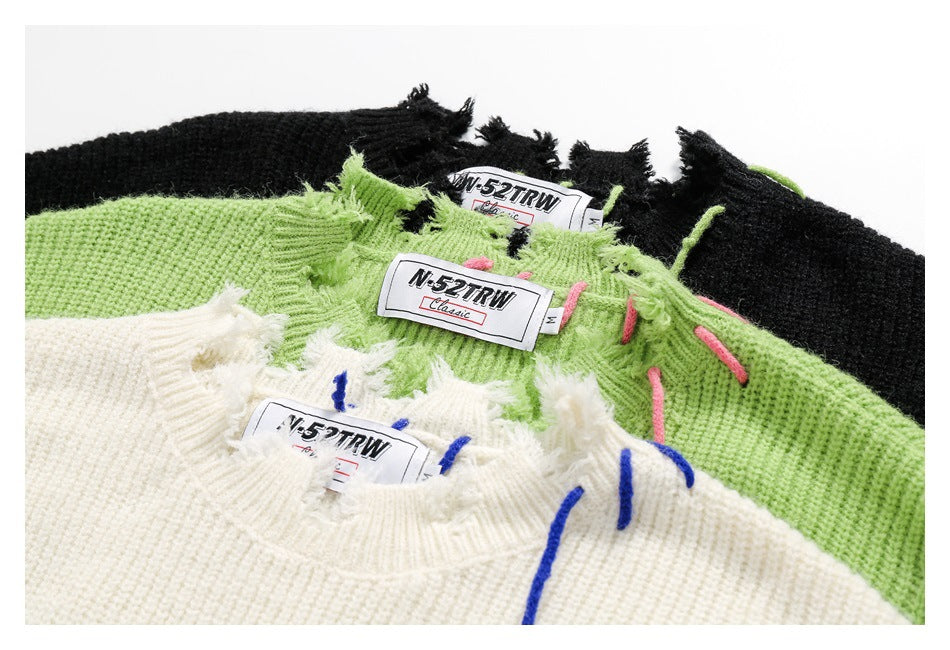 Close-up of black, green, and ivory sweater necklines with distressed edges, colorful stitching, and sewn labels.