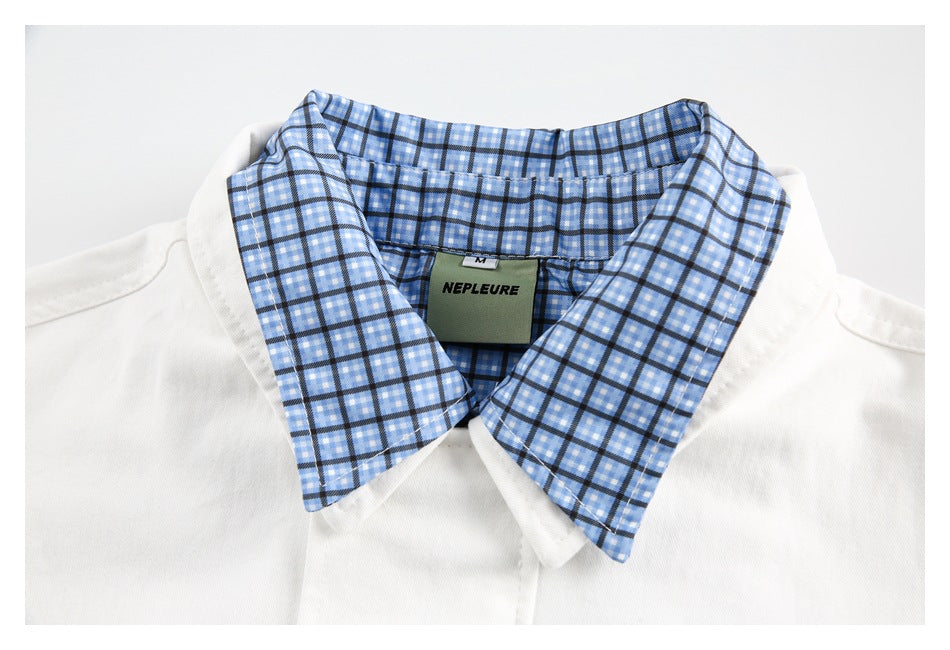 Close-up of a white jacket collar lined with blue checked fabric, showing a sewn-in label.