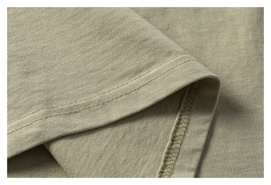 Close-up of a beige garment hem and overlocked seam with visible stitching.