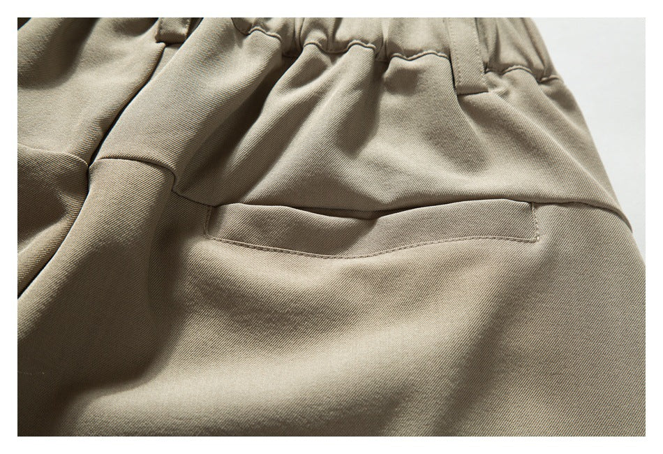 Close-up of a taupe trouser back with a gathered waistband and horizontal welt pocket.