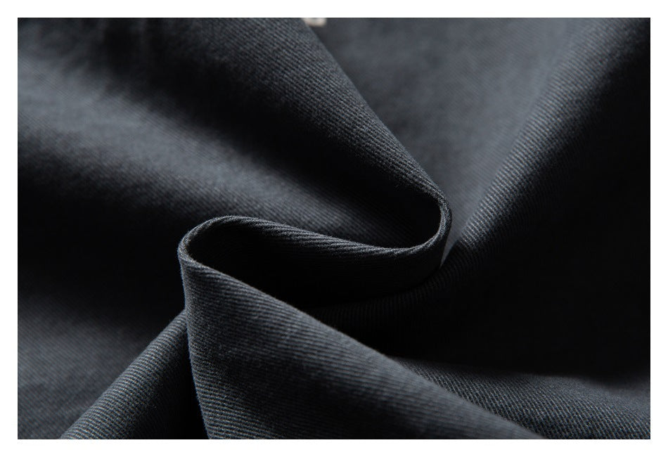 Close-up of dark charcoal fabric folded into soft curves, showing its fine diagonal weave.