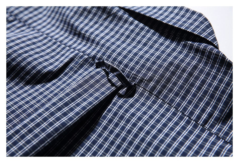 Close-up of navy-and-white plaid shirt fabric showing a stitched seam and folded placket.