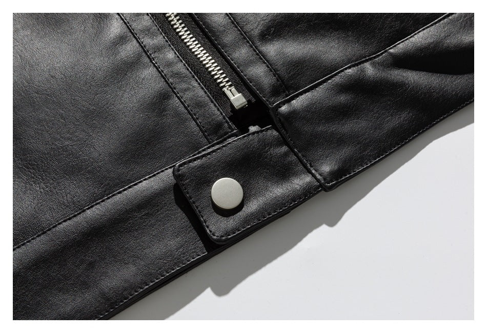 Close-up of a black jacket with a silver zipper, stitched paneling, and a snap-fastened tab.