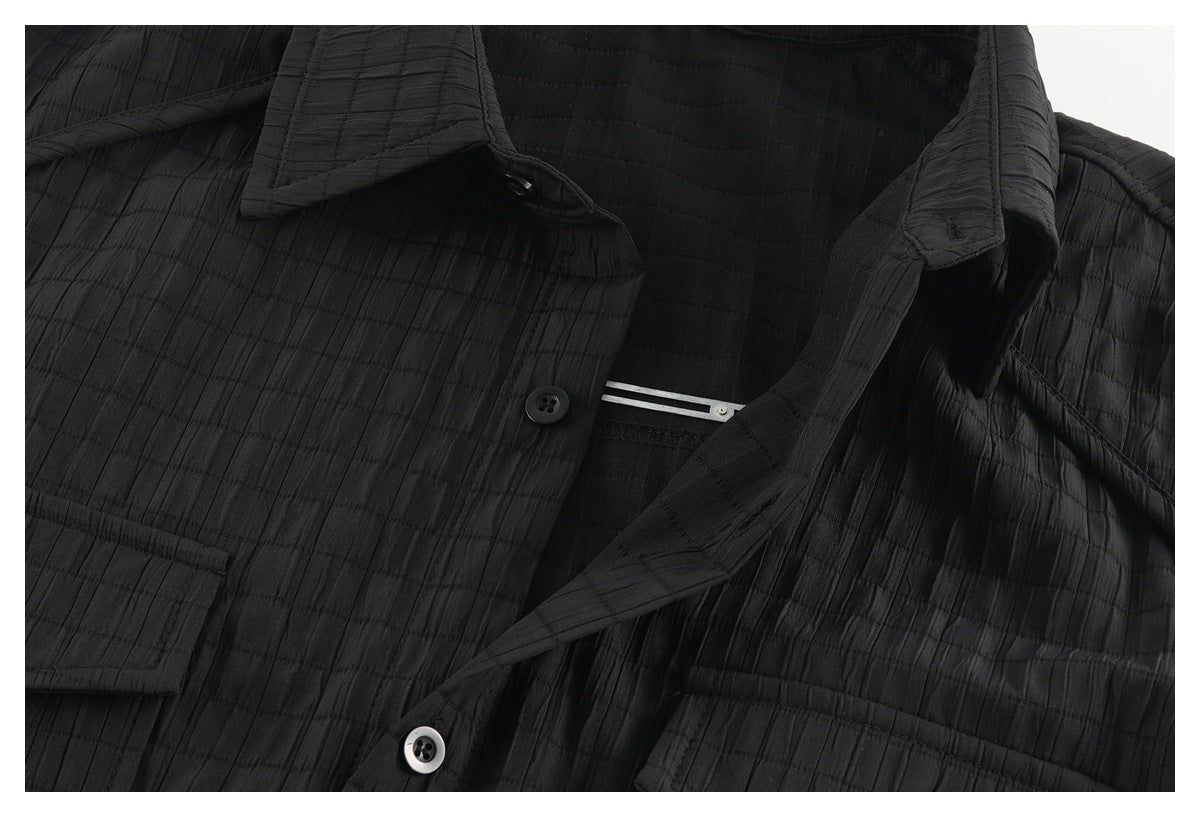 Close-up of a black shirt's open collar, button placket, and flap pockets.