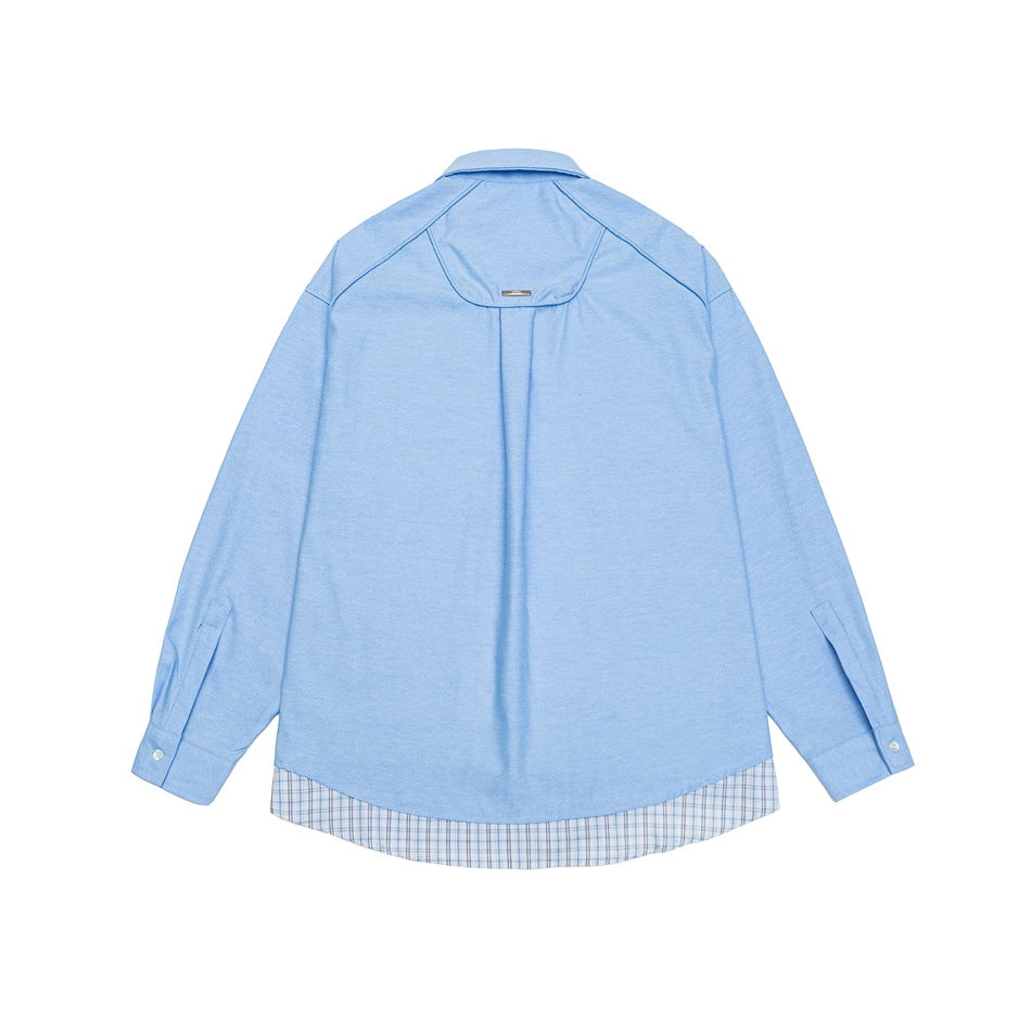 Back view of a light blue shirt with a curved yoke and plaid fabric along the hem.