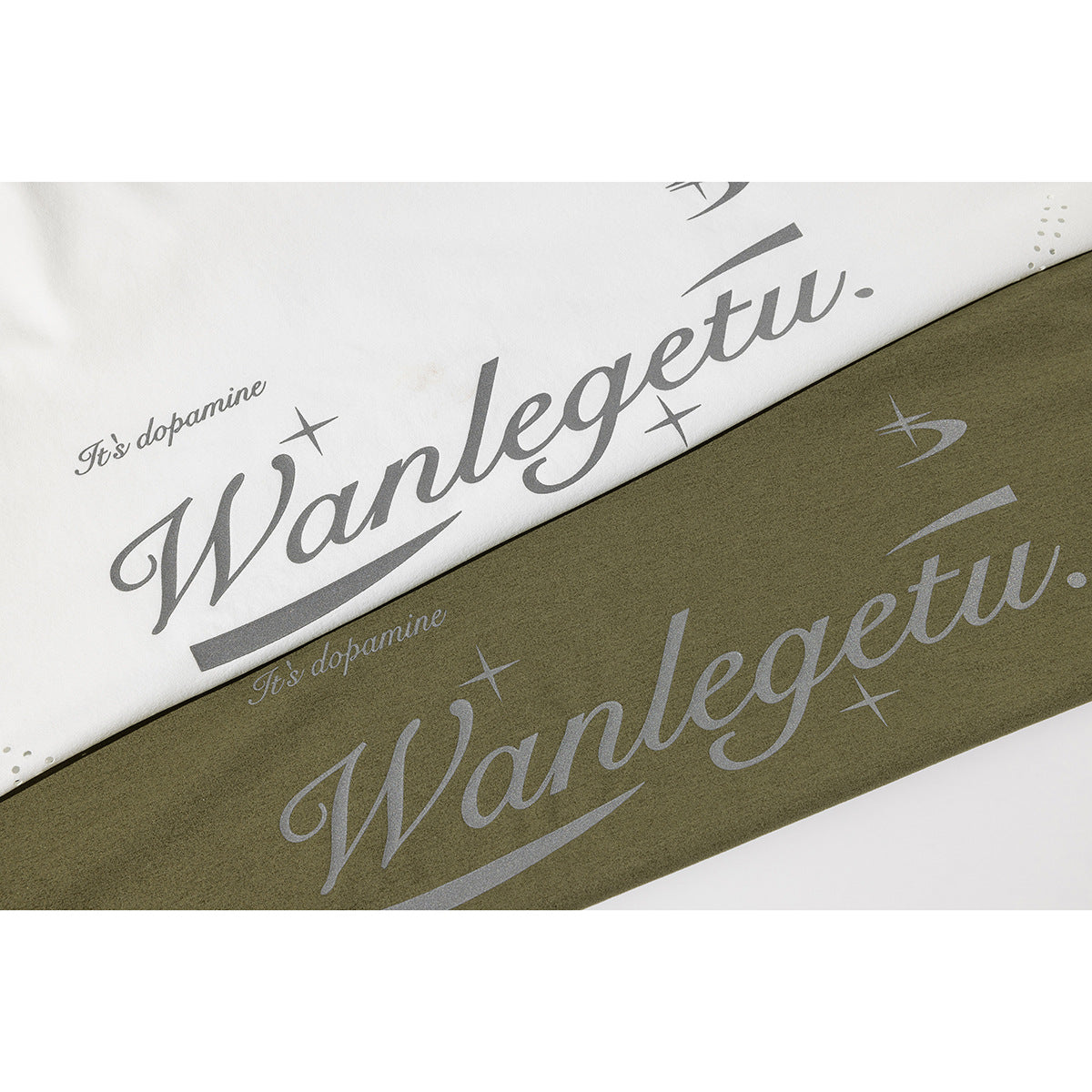 Close-up of white and olive-green T-shirts with large gray script graphics on the front.