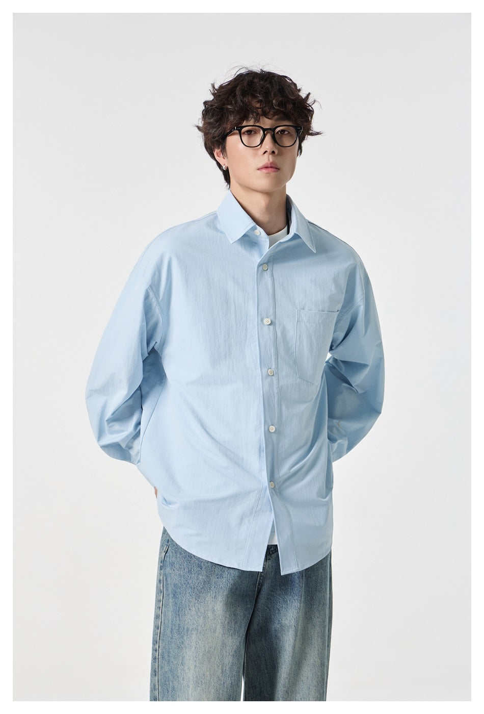 Front view of a model wearing an oversized pale blue button-up shirt with a chest pocket and white buttons.