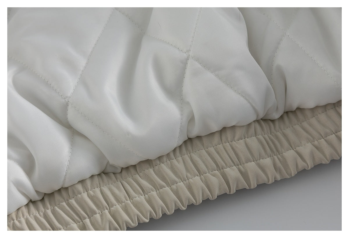 Close-up of ivory quilted coat fabric above a gathered elasticized hem.