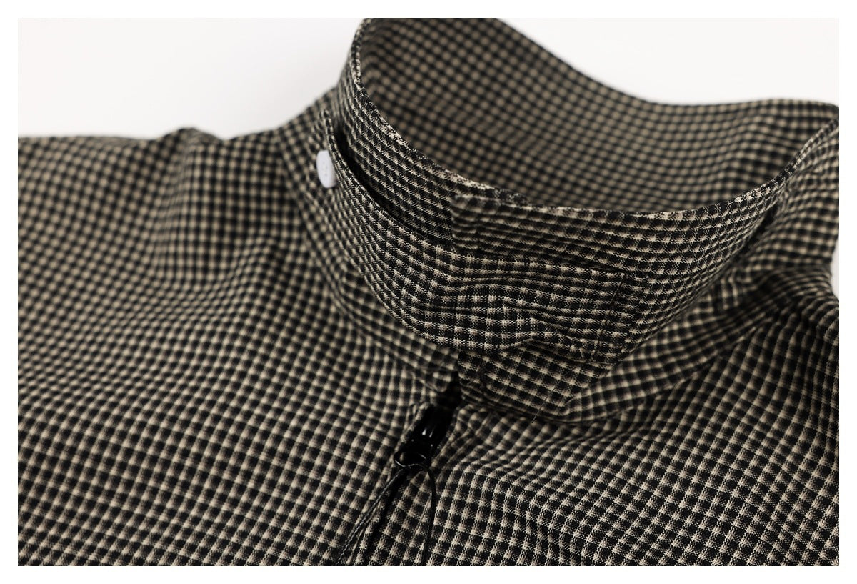 Close-up of a standing collar and black zipper on a black and beige small-check garment.