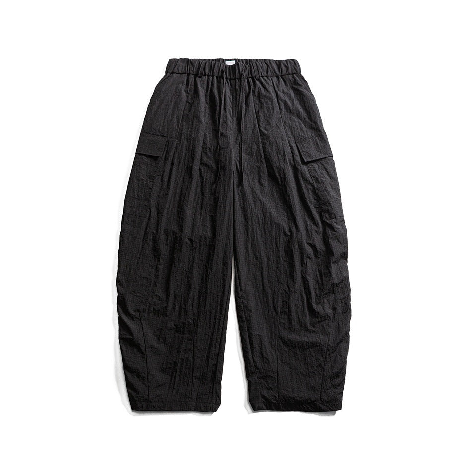 Black wide-leg cargo pants with elastic drawstring waist and side flap pockets, flat lay on white background