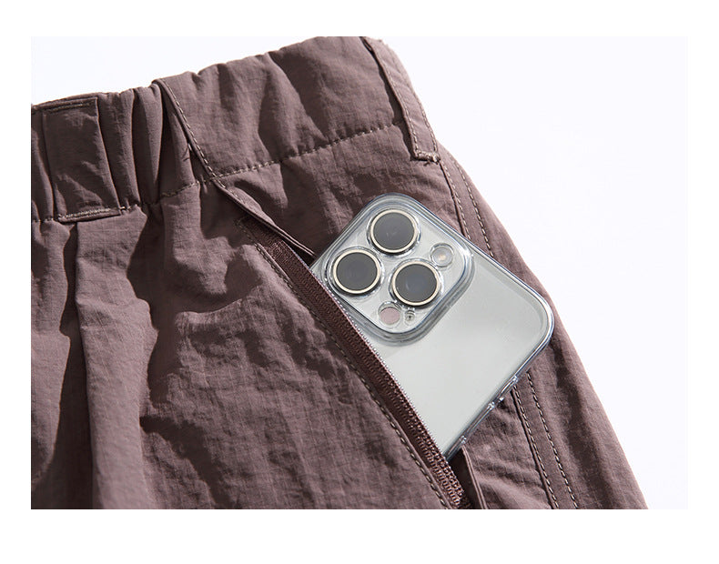 Close-up of a zippered pocket on mauve pants with a smartphone tucked inside.