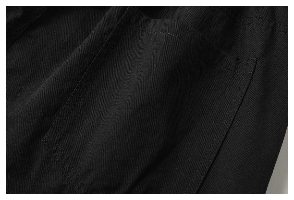 Close-up of a stitched patch pocket on black fabric.