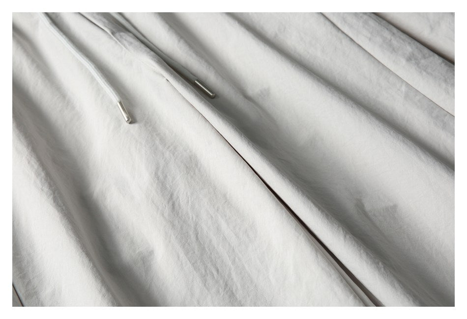 Close-up of light gray shorts with white drawstrings and metal tips against the fabric.