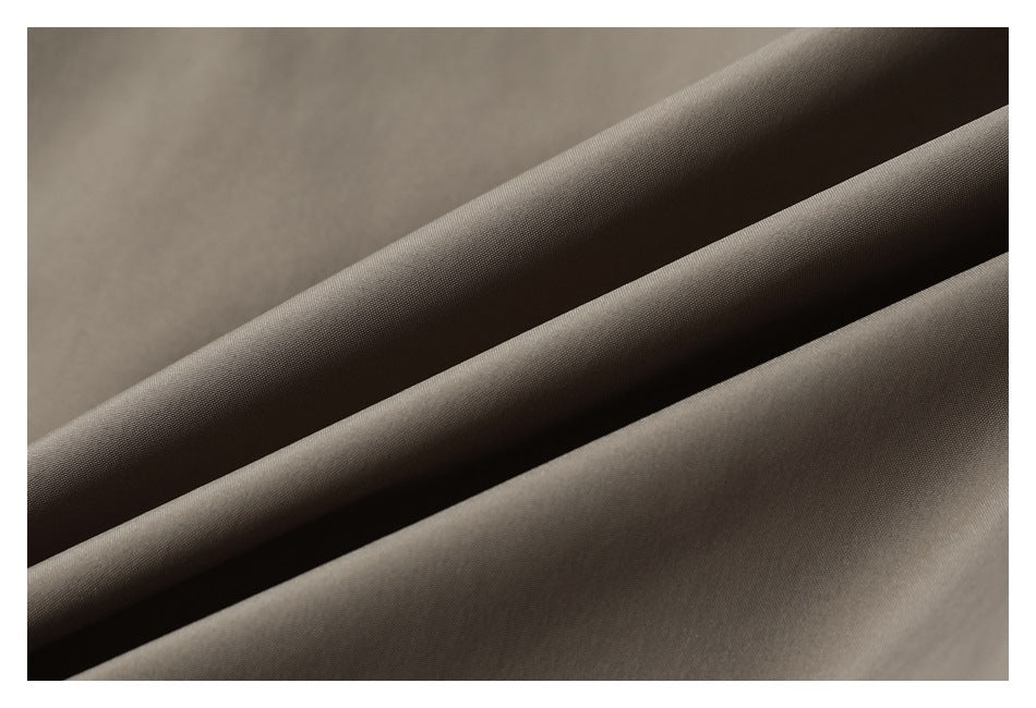 Close-up of taupe fabric draped in folds, showing its fine surface texture.