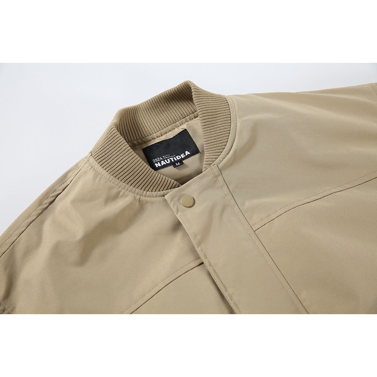 Close-up of a tan bomber jacket's ribbed collar, snap-front placket, stitching, and sewn-in neck label.