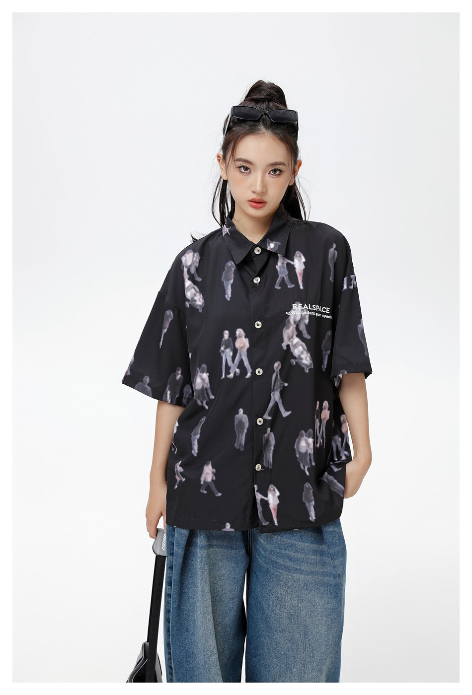 Closer view of a model wearing a black short-sleeve shirt with an all-over figure print and white chest lettering.