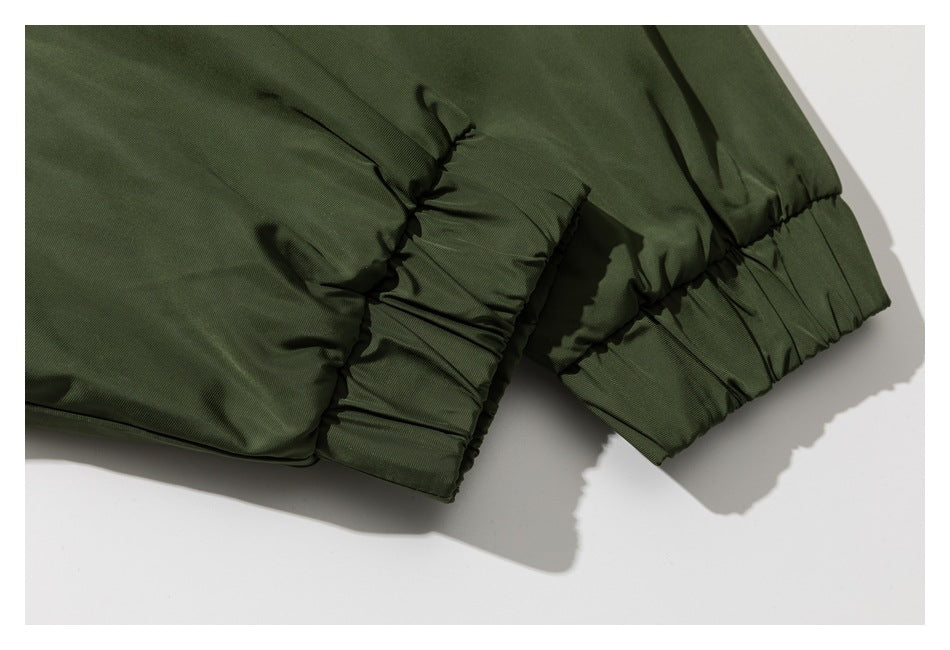 Close-up of a dark olive jacket sleeve and body, showing gathered elastic cuffs and a seam.