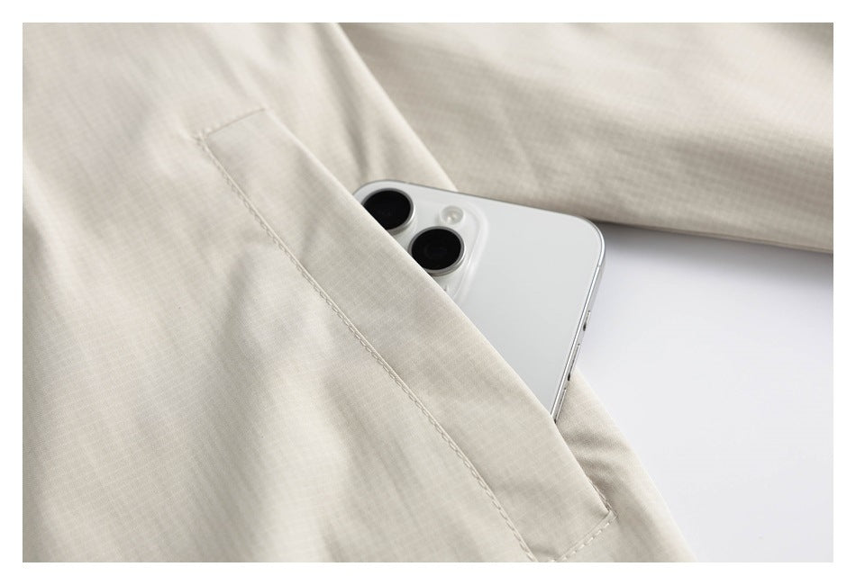 Close-up of a phone tucked into a stitched pocket on the cream jacket.