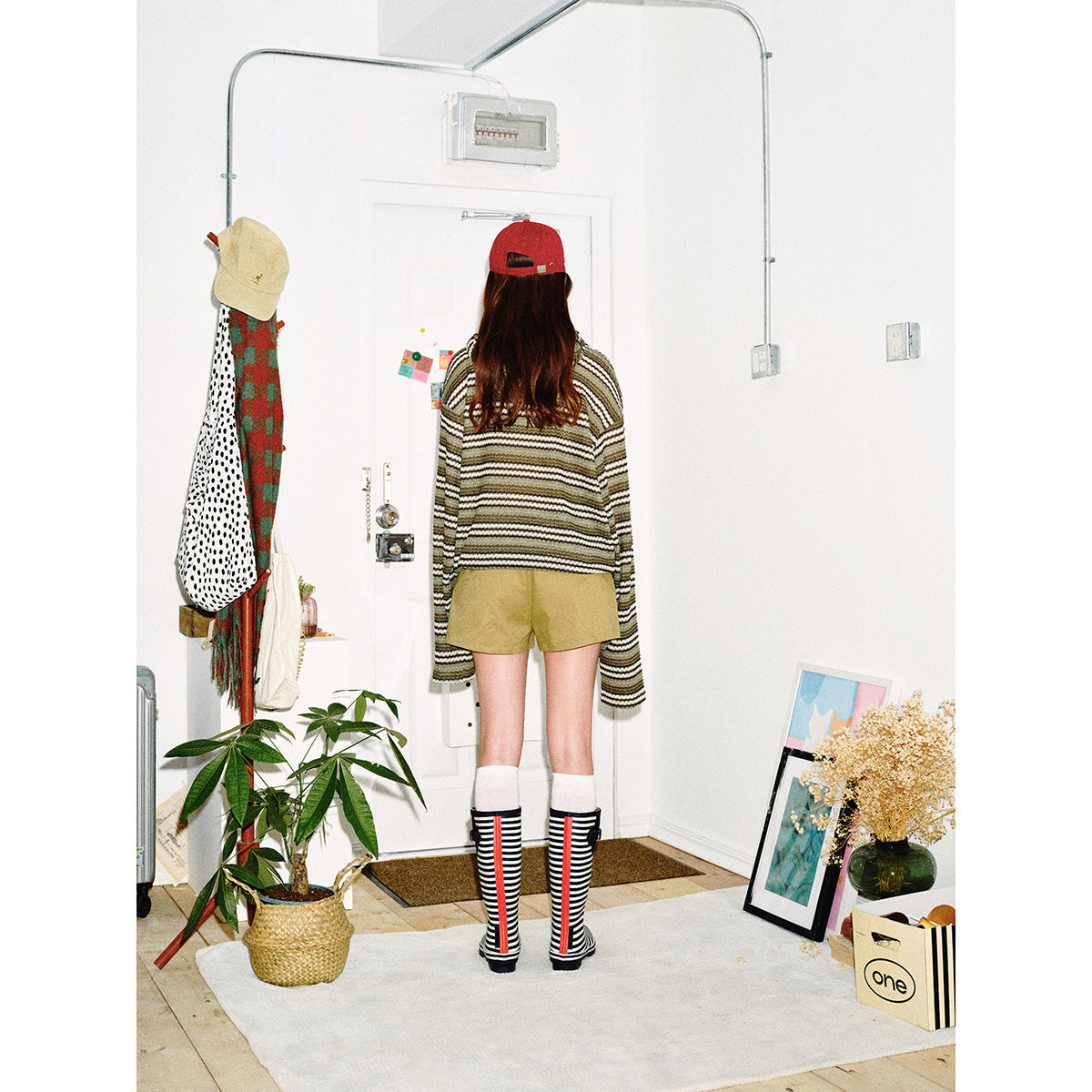 Back view of a model wearing a striped hooded pullover and olive shorts.