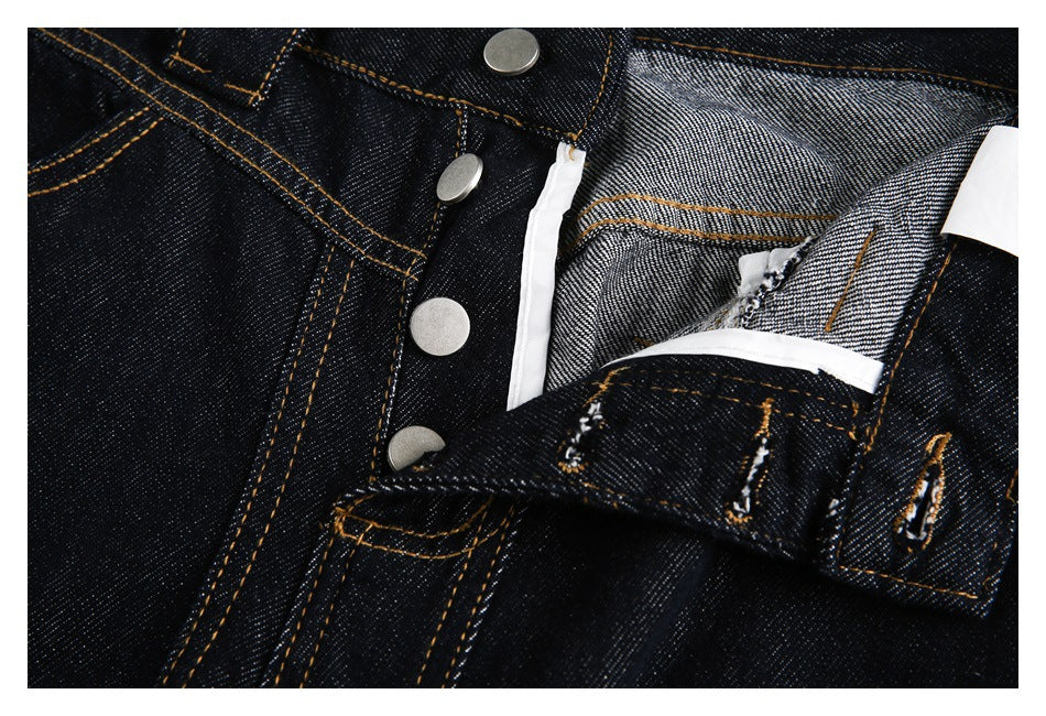 Close-up of dark indigo jeans with the button fly opened, revealing the inner denim and fly facing.
