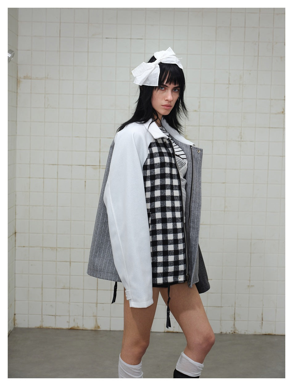 Three-quarter view of a model wearing a patchwork jacket with white sleeves, a check panel and gray pinstripes.