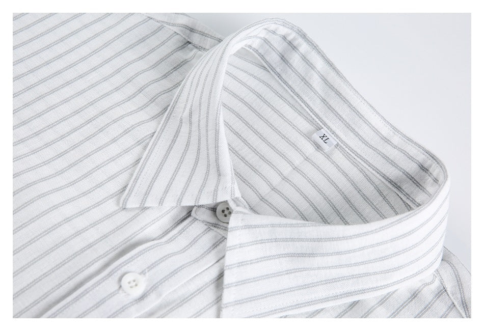 Close-up of a white shirt with fine gray stripes, showing its pointed collar, buttons, and inner collar label.