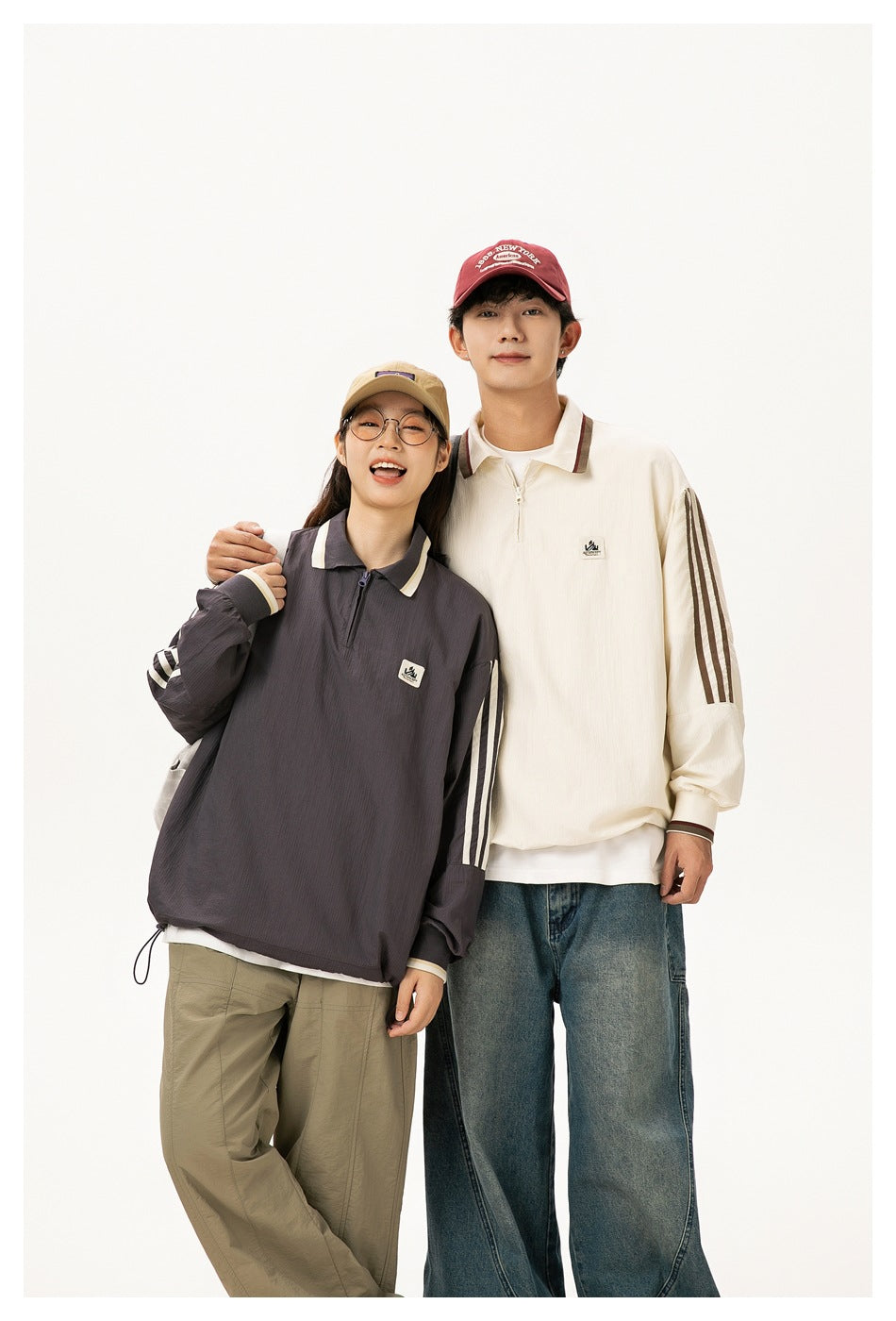Closer view of two models wearing charcoal and cream oversized quarter-zip pullovers with contrasting sleeve stripes.