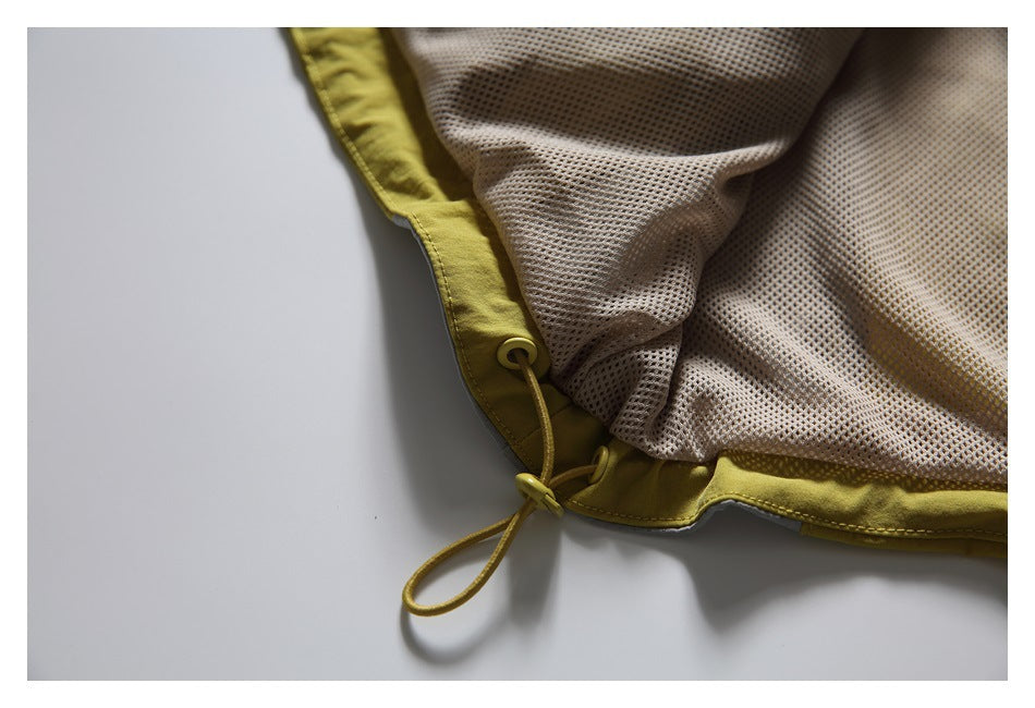 Close-up of a mustard-yellow garment hem with an adjustable drawcord and mesh lining.