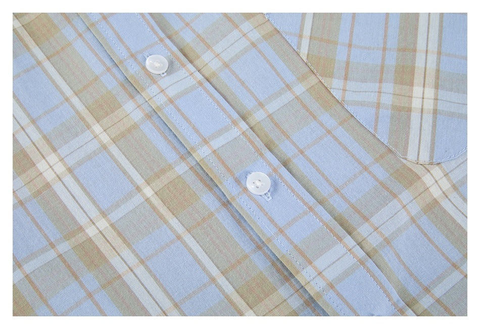 Close-up of the shirt's plaid front placket, white buttons and edge of the chest pocket.