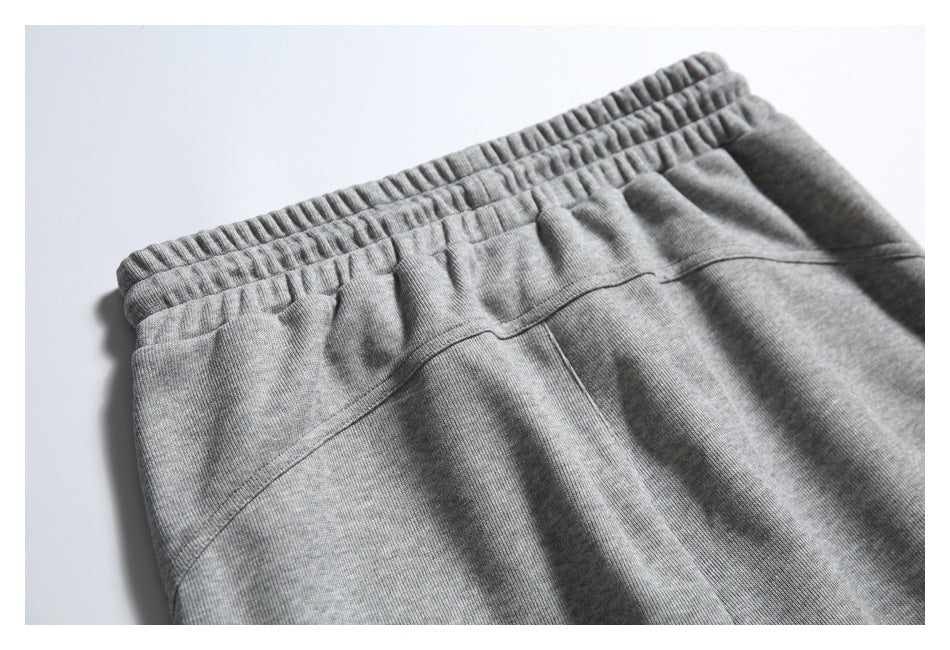 Close-up of gray pants showing a gathered elastic waistband and curved seam.