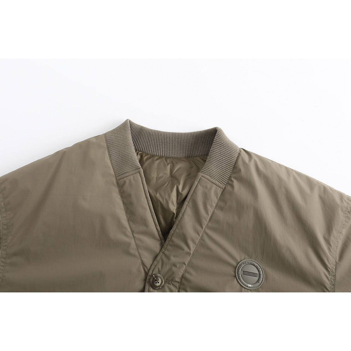 Close-up of an olive-taupe jacket showing its ribbed V-neck collar, button placket, and round chest patch.