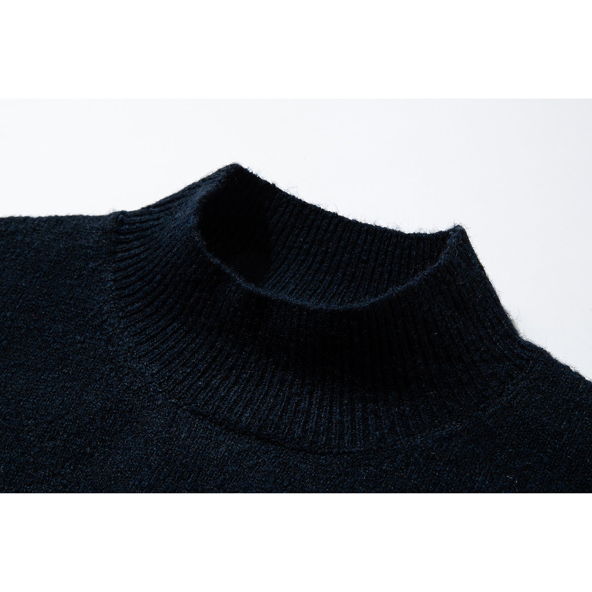 Close-up of a dark navy knit sweater's ribbed mock neck and shoulder.
