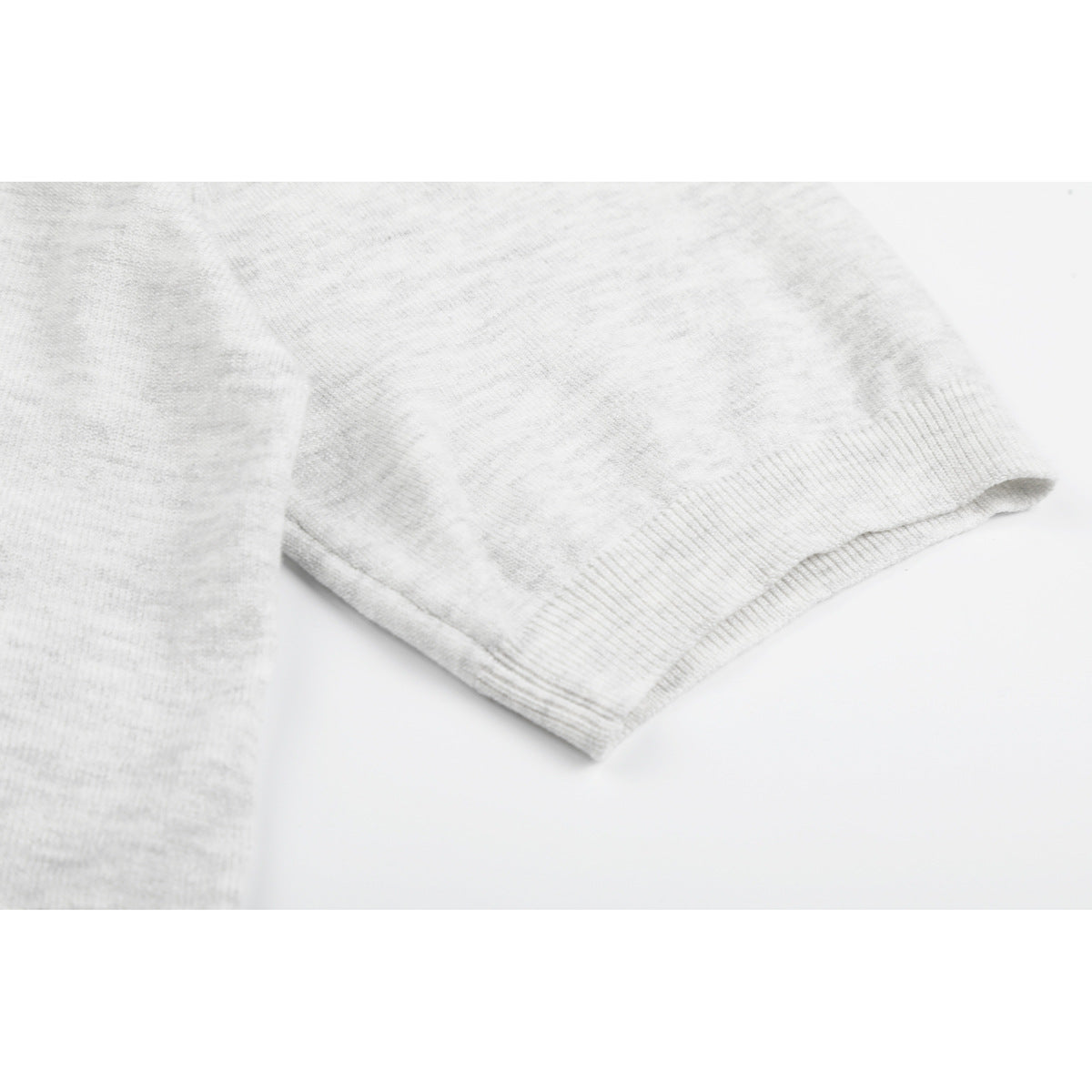 Close-up of the light gray knit polo's short sleeve and ribbed cuff.
