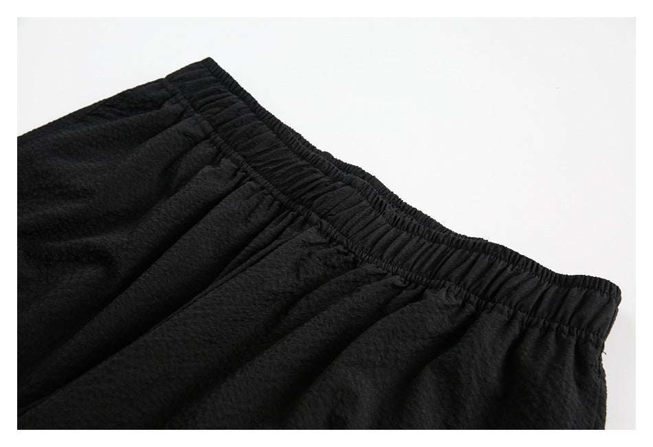 Close-up of black shorts showing the gathered elastic waistband and textured fabric.