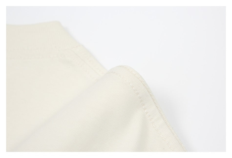 Close-up of a curved, stitched edge on ivory fabric.