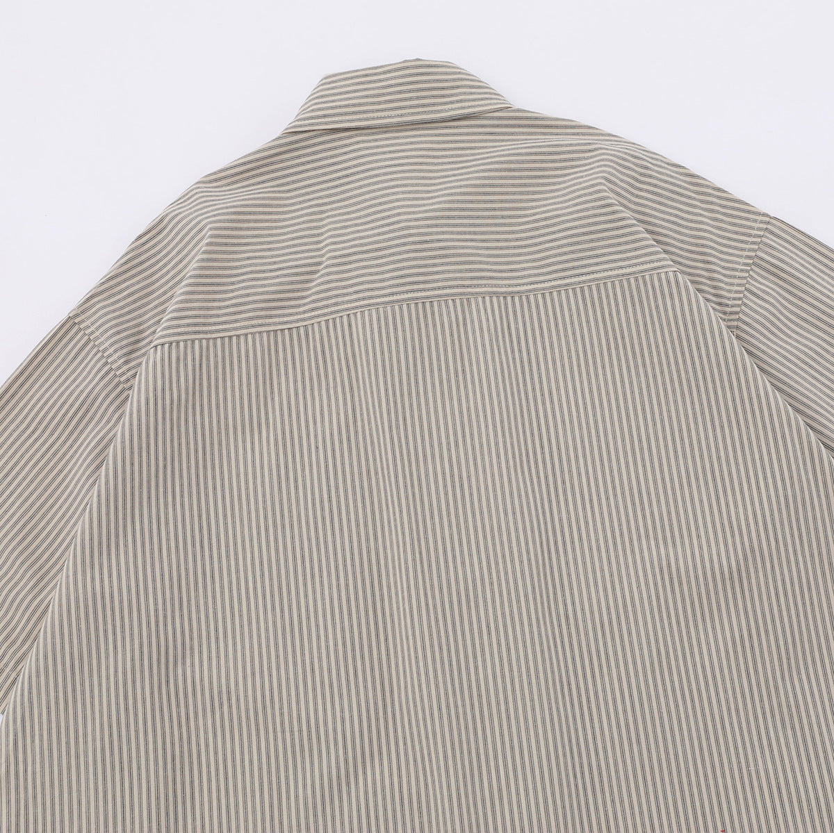 Back of a beige short-sleeve shirt with narrow stripes and a horizontal yoke seam, laid flat.