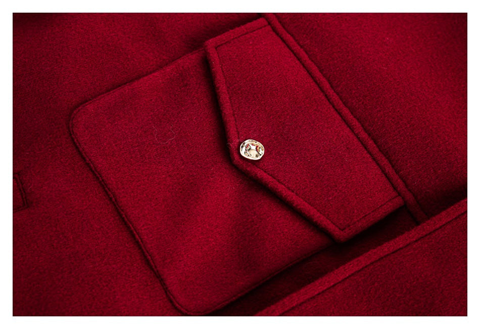 Close-up of a burgundy coat's flap pocket with a gold-tone button.