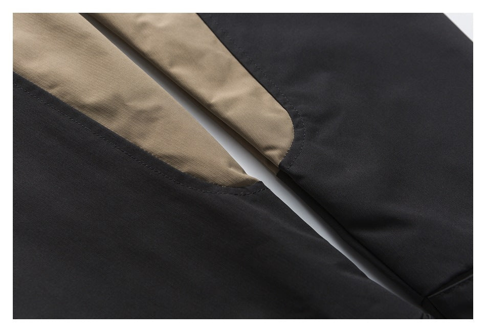 Close-up of black jacket panels with tan inset sections and curved stitched seams.