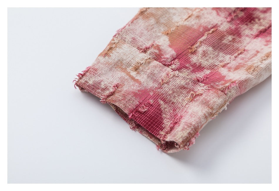 Close-up of the cuff edge and frayed plaid fabric on a pink, cream and tan shirt.