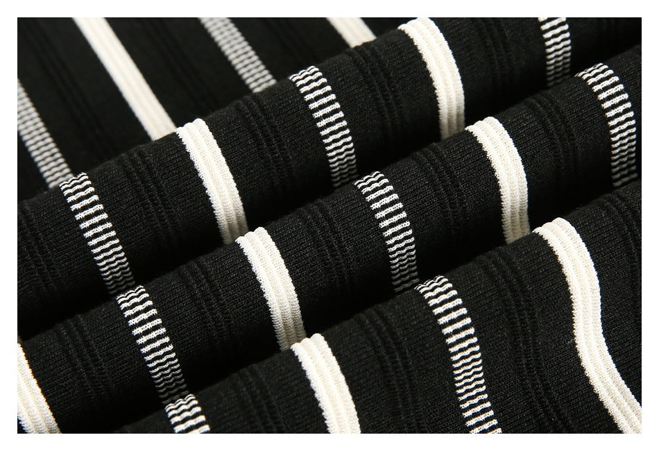Close-up of black knit fabric with repeating narrow and wide white horizontal stripe bands.