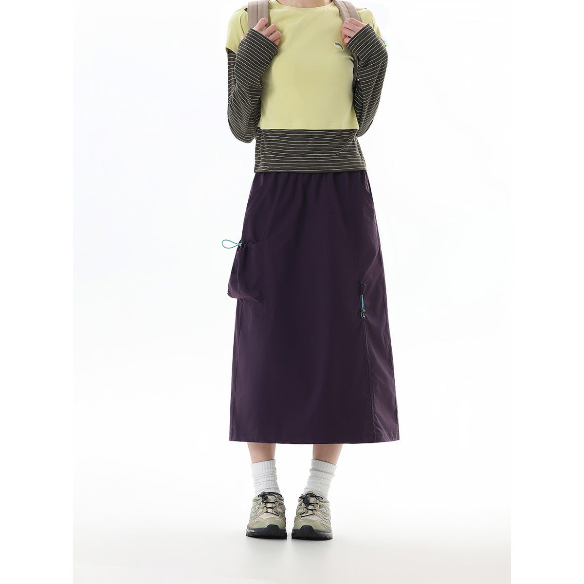 Front view of a model wearing a dark purple midi skirt with side pockets and a yellow-green layered top.
