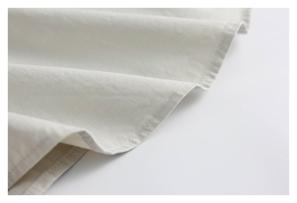 Close-up of an off-white garment hem with neat stitching and folded fabric.