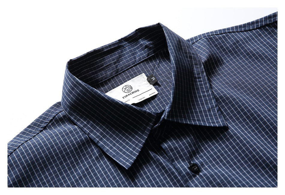 Close-up of a navy grid-check shirt collar, inner neck label, and top button.
