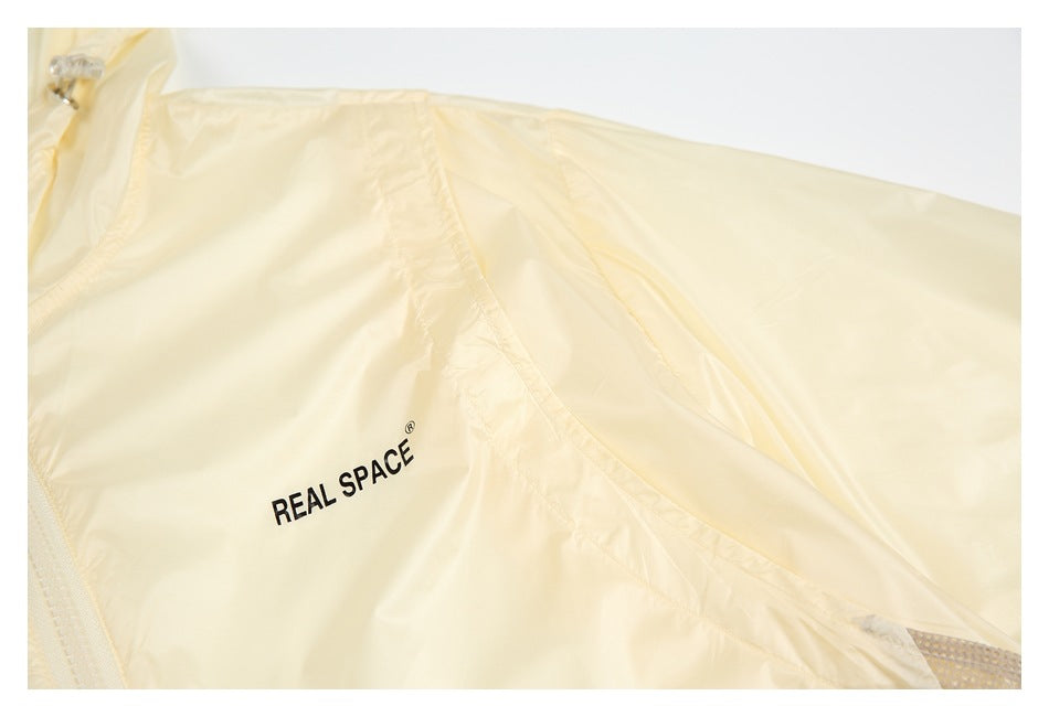 Close-up of a pale cream jacket sleeve and body with black REAL SPACE lettering.